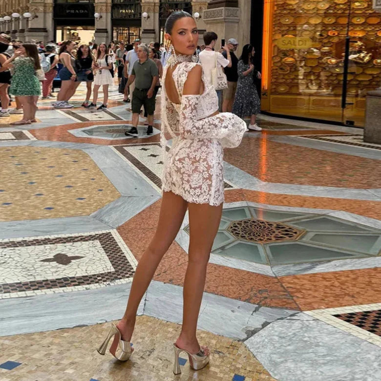 Woman in a white lace outfit posing in a bustling indoor shopping area.