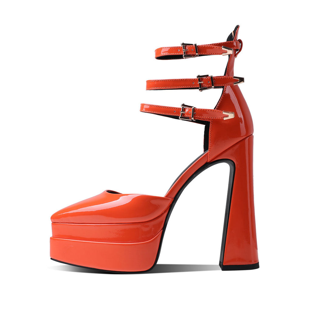 A pair of orange glossy pointed toe platform block heel ankle strap pumps.