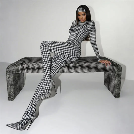 Person wearing a black and white checkered outfit sitting on a matching bench against a white background