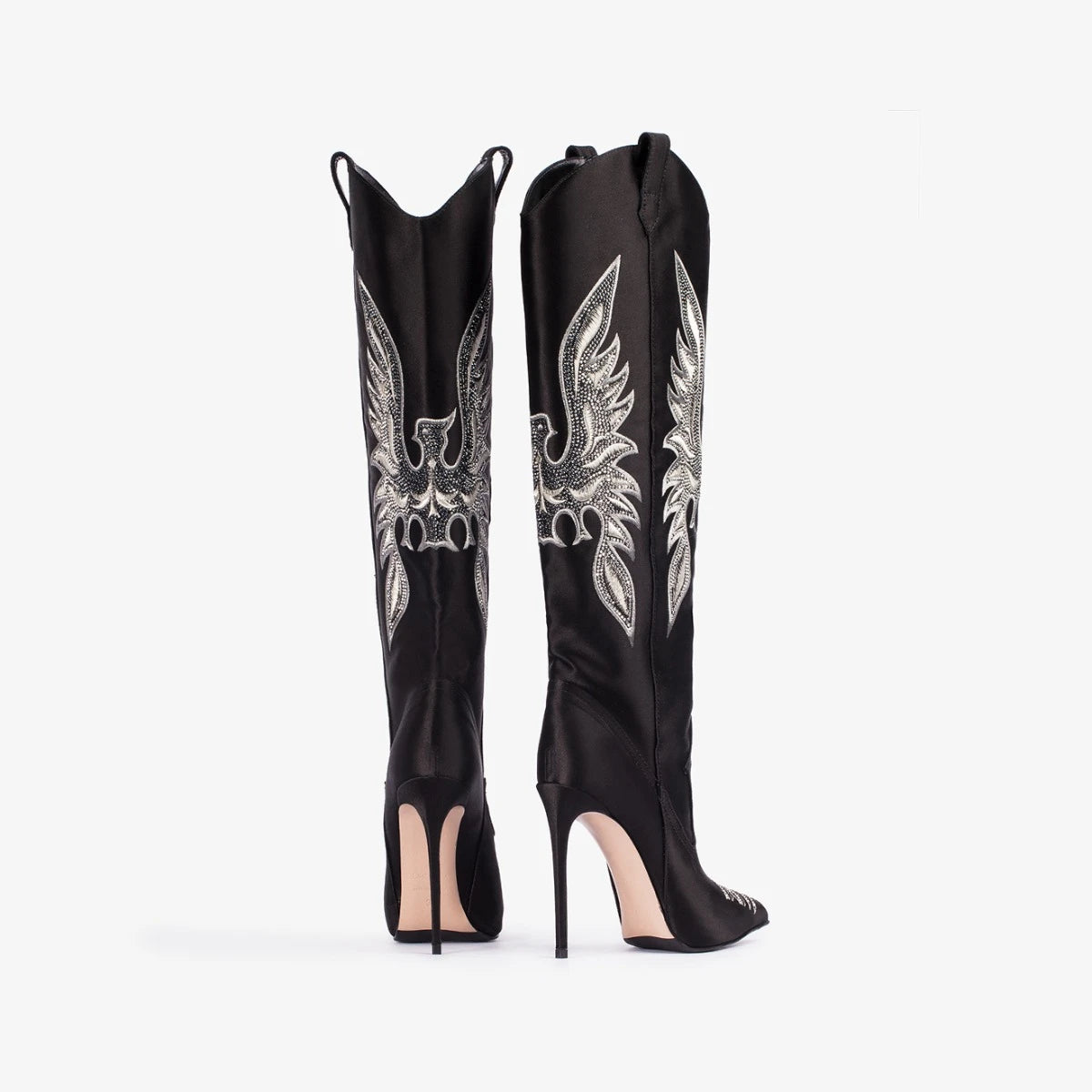 Black knee-high boots with silver winged creature design on a white background