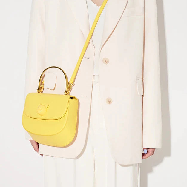 Person holding a yellow handbag against a white background
