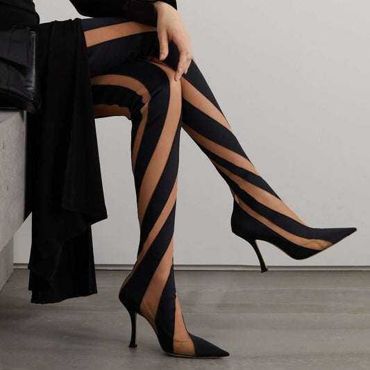 A pair of black mesh high boots with stripes, featuring a rubber outsole and PU insole, displayed against a white background with a person seated in the background wearing a black dress.